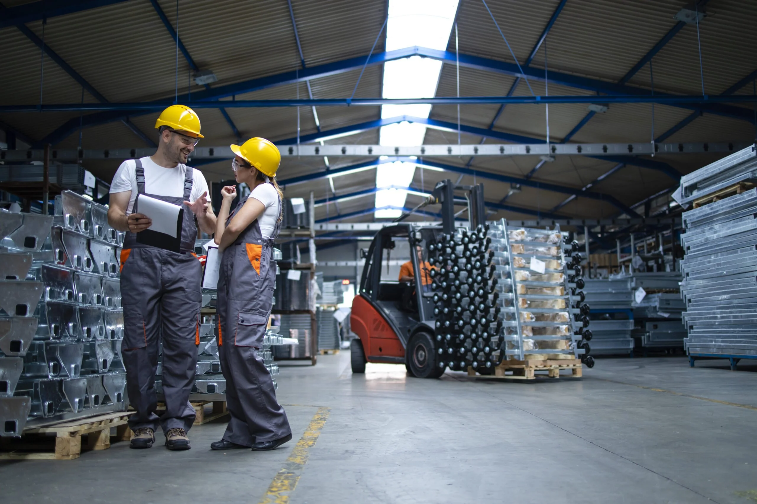 Factory workers standing in industrial warehouse and discussing about production.